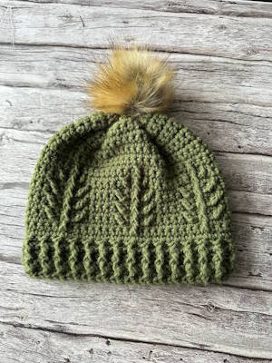Textured evergreen crochet winter hat with pom pom and front post stitch pattern