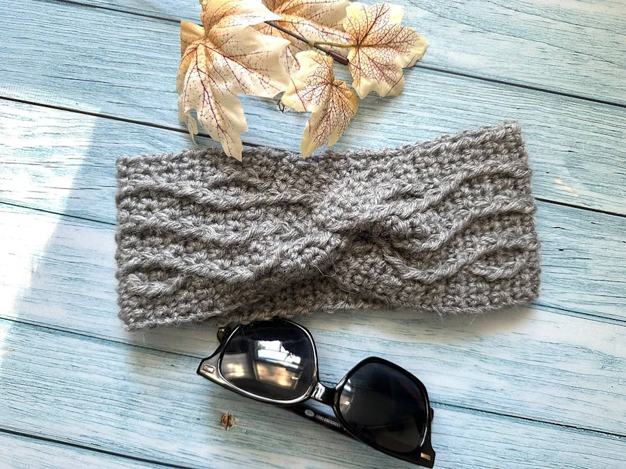 Twisted cable weave crochet headband styled as a cozy winter ear warmer for women
