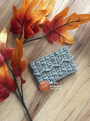 Textured crochet cup cozy Mountain Trail pattern, coffee sleeve design with soft cable style stitches on wooden background Preview