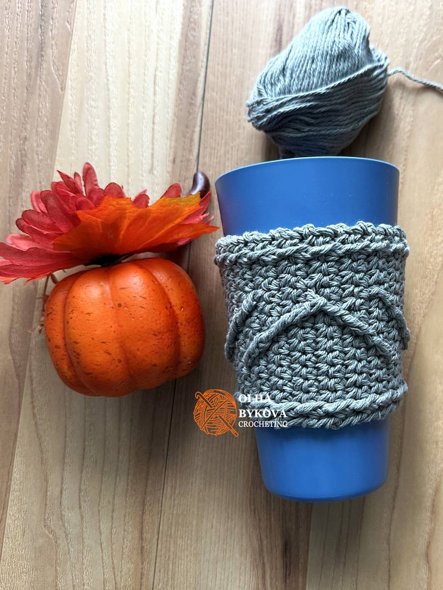 Crochet coffee sleeve with textured chevron design next to pumpkin, fall crochet cup cozy pattern