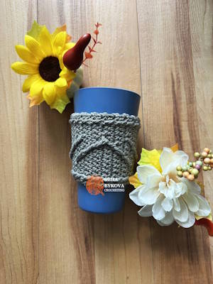 Textured crochet cup cozy on coffee cup with flowers, easy crochet coffee sleeve pattern preview