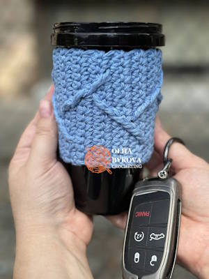 crochet coffee sleeve on travel cup held in hand, textured mountain peaks pattern preview