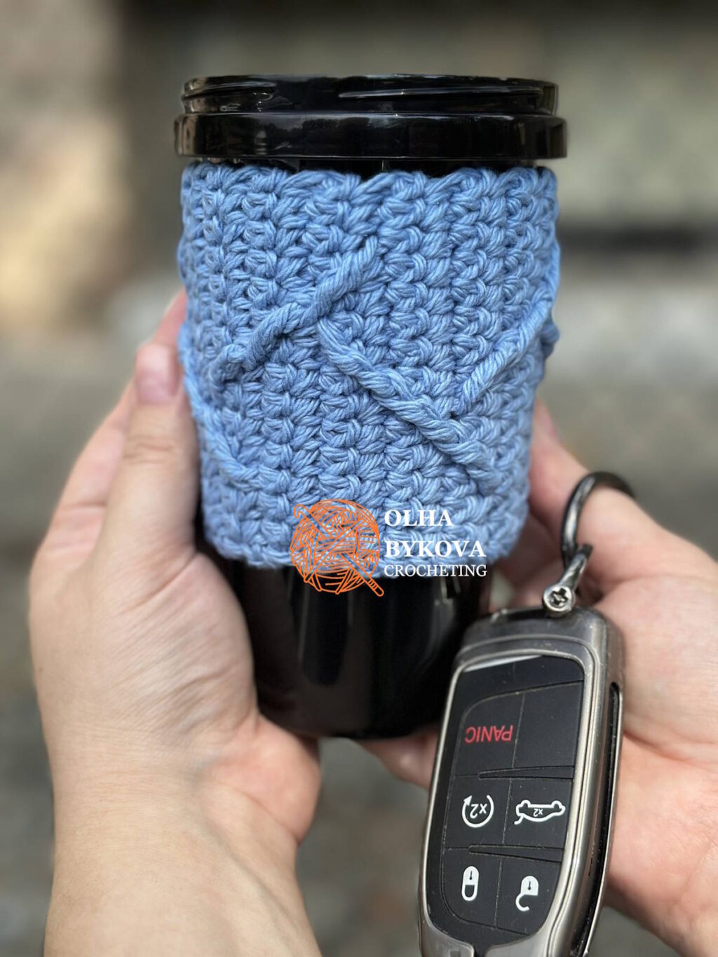 crochet coffee sleeve on travel cup held in hand, textured mountain peaks pattern