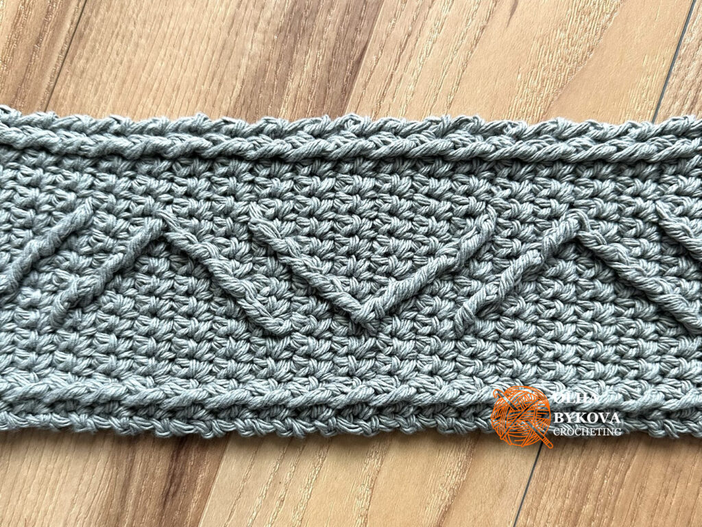 Close-up of textured crochet cup cozy with chevron cable stitch detail, aran style crochet texture