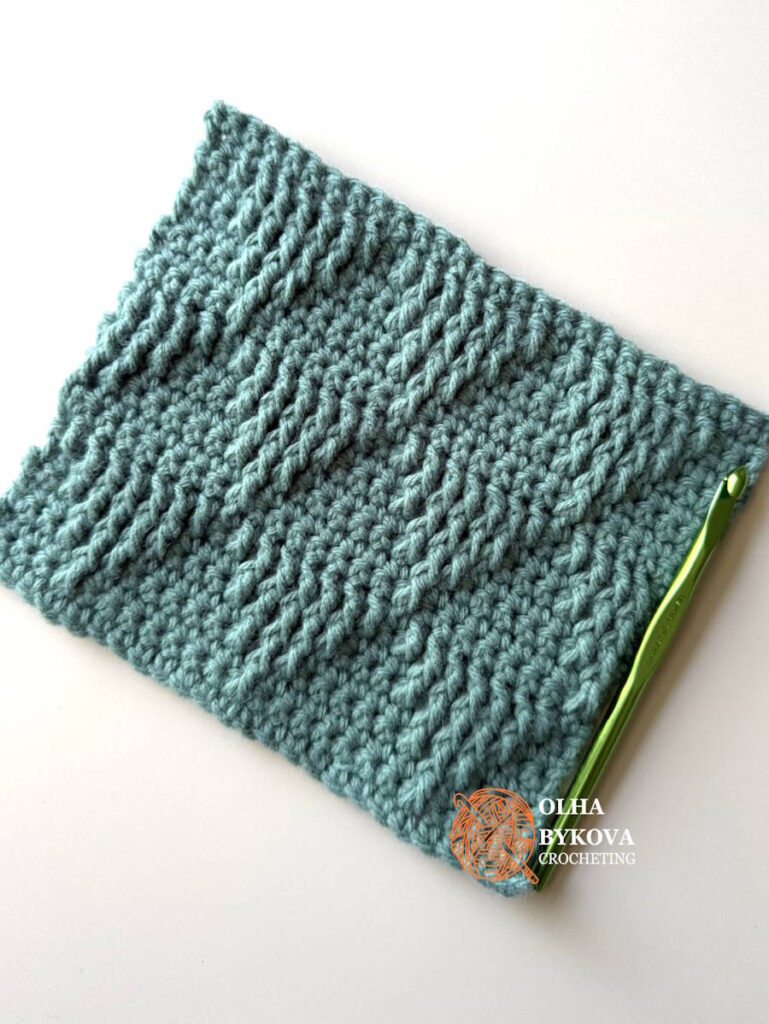 Shadow Basket Weave Triangle Crochet Stitch sample with crochet hook, demonstrating a textured crochet stitch pattern with repeating triangle shapes.