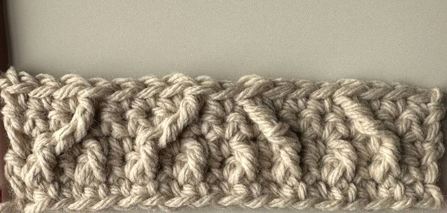 Row 5 of a cable crochet headband pattern showing raised post stitches developing into a textured cable design