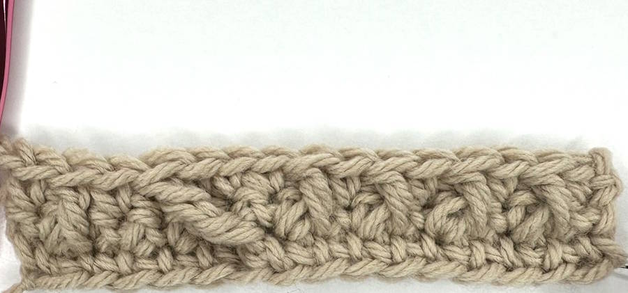 Row 3 of a crochet headband pattern showing raised front post stitches beginning the textured ear warmer design