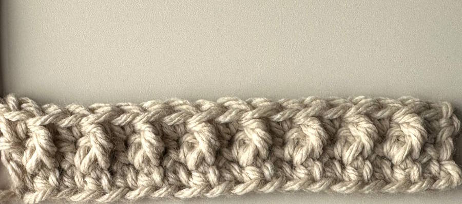 Row 3 of a textured crochet headband pattern showing raised front post crochet stitches forming the beginning of the design